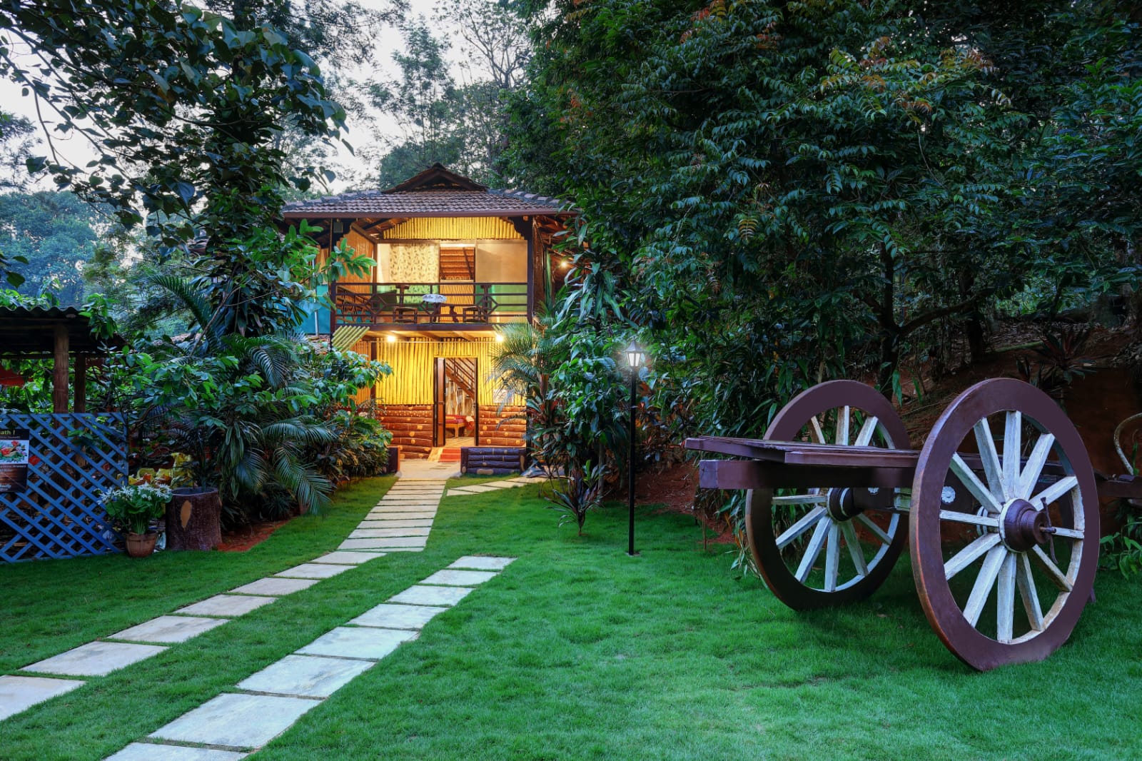 Rustic wooden cottage with vintage cart wheels set in lush forest greenery