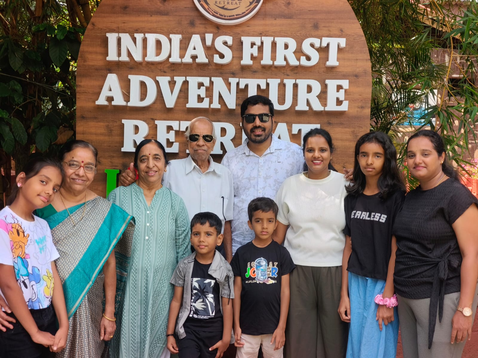 A large family group in life jackets holding paddles by a lake at Evergreen County resort in Coorg.