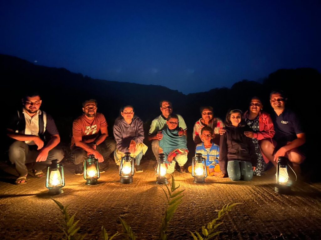 Guests enjoying a night plantation walk with lanterns at Evergreen County, a premier adventure resort in Coorg.