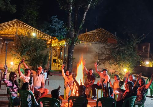 Guests enjoying a campfire at Evergreen County Resort, a premier nature retreat and pure veg resort in Coorg, following a night plantation walk.
